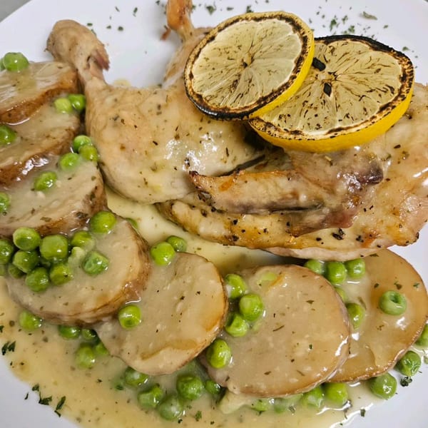 Roasted chicken with grilled lemon slices, potatoes, and green peas in a creamy sauce.