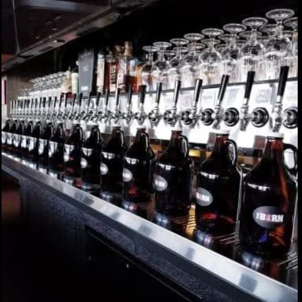 A long row of beer taps and growlers with "BARN" labels at The Red Barn Brewery.
